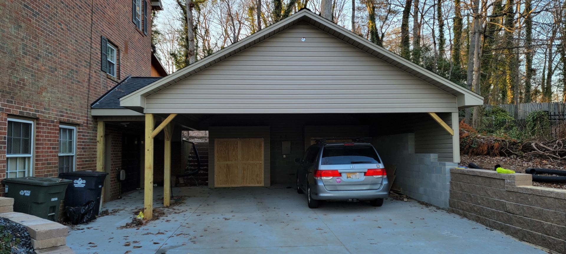 A car is parked under a carport in front of a house.