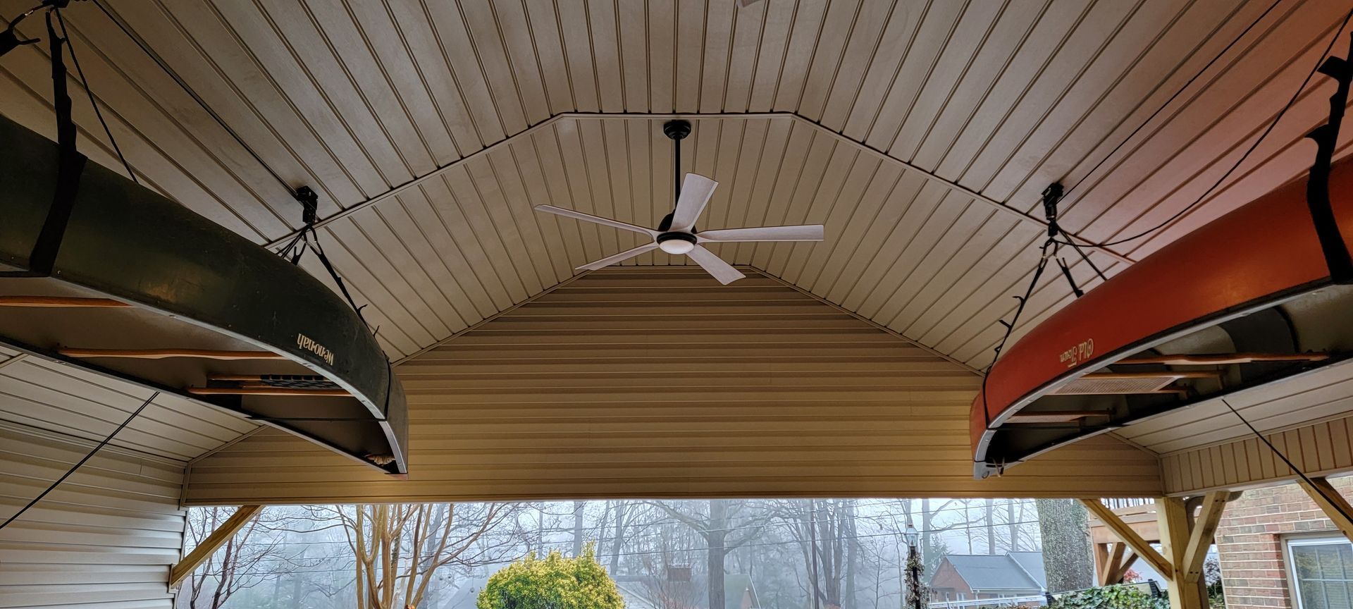 Two canoes are hanging from the ceiling of a building with a ceiling fan.
