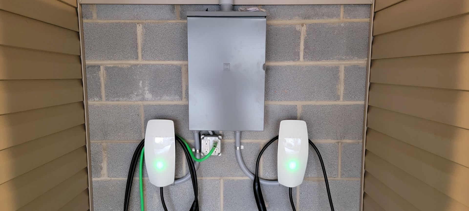 Two electric vehicle charging stations are installed on a brick wall.
