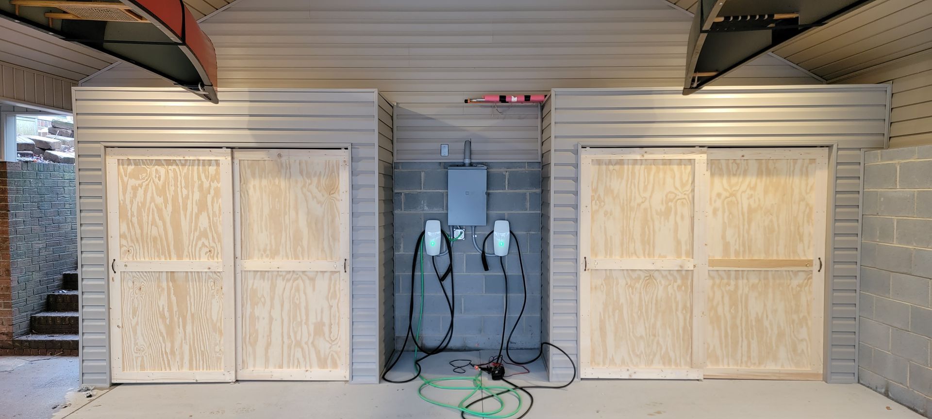 A garage with sliding wooden doors and a hose