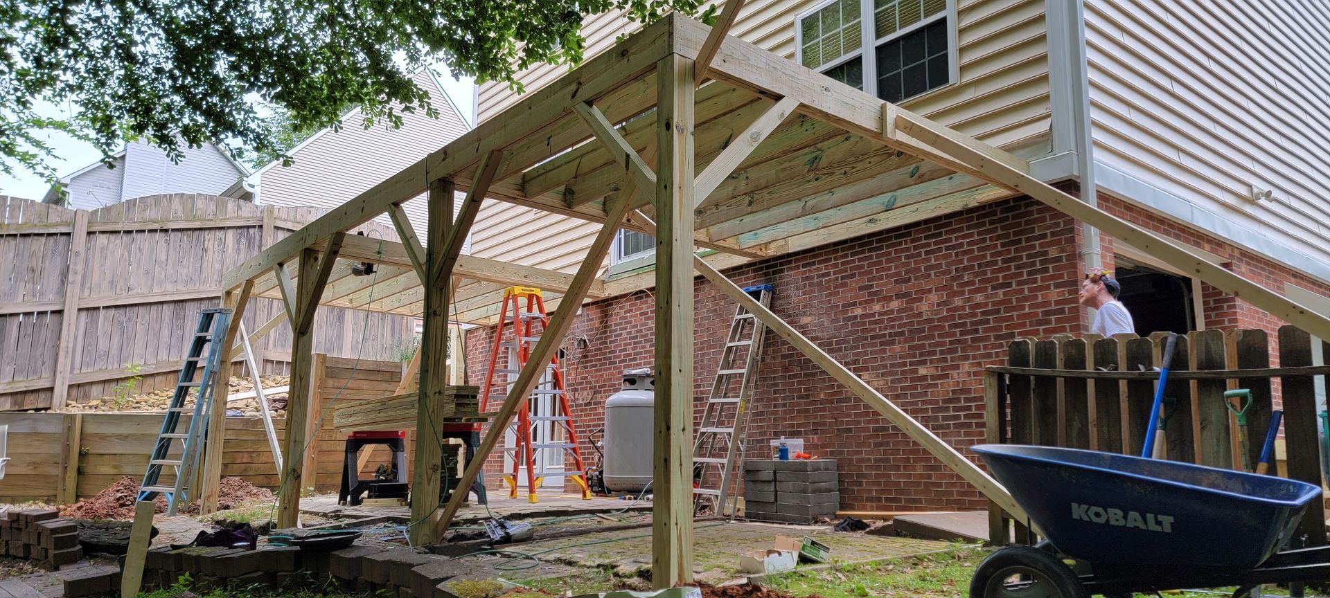 A wooden deck is being built in the backyard of a house.