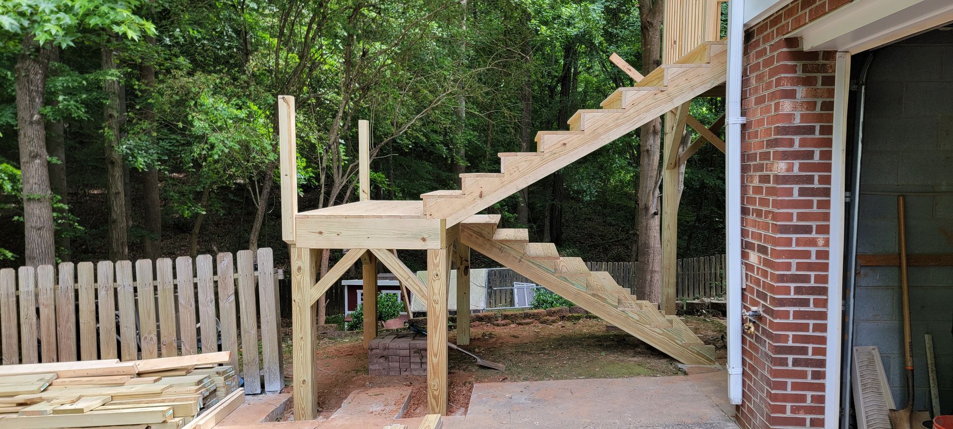 A wooden staircase is being built in the backyard of a house.