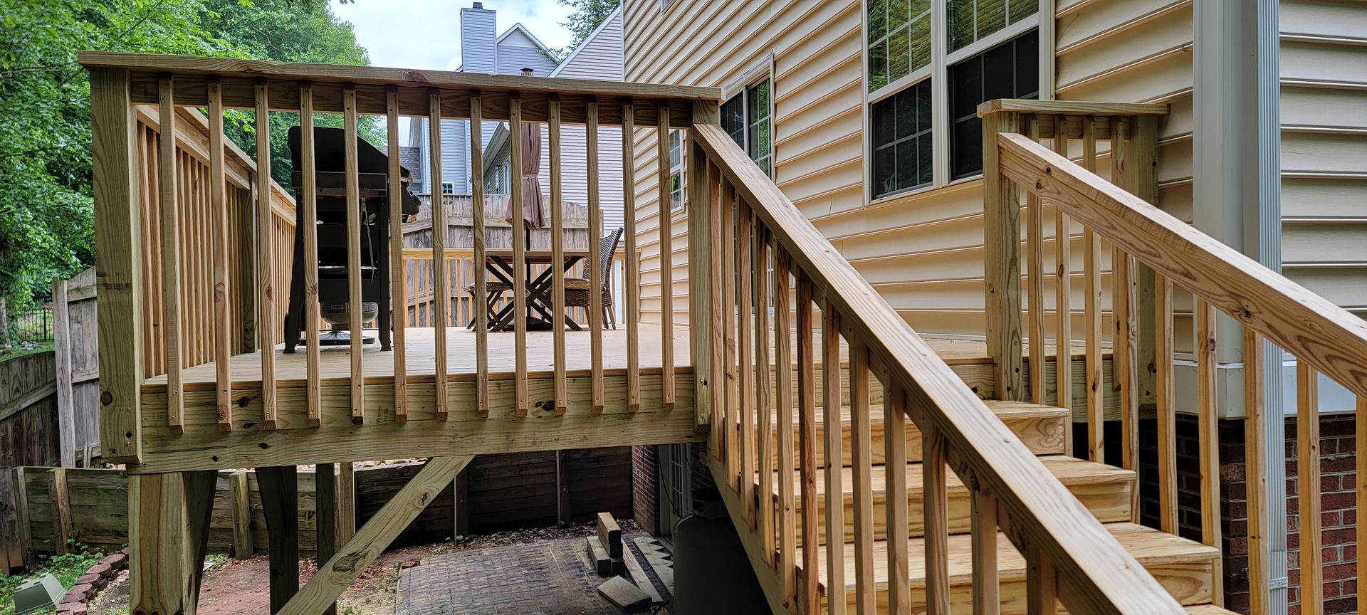 A wooden deck with stairs leading up to it and a house in the background.