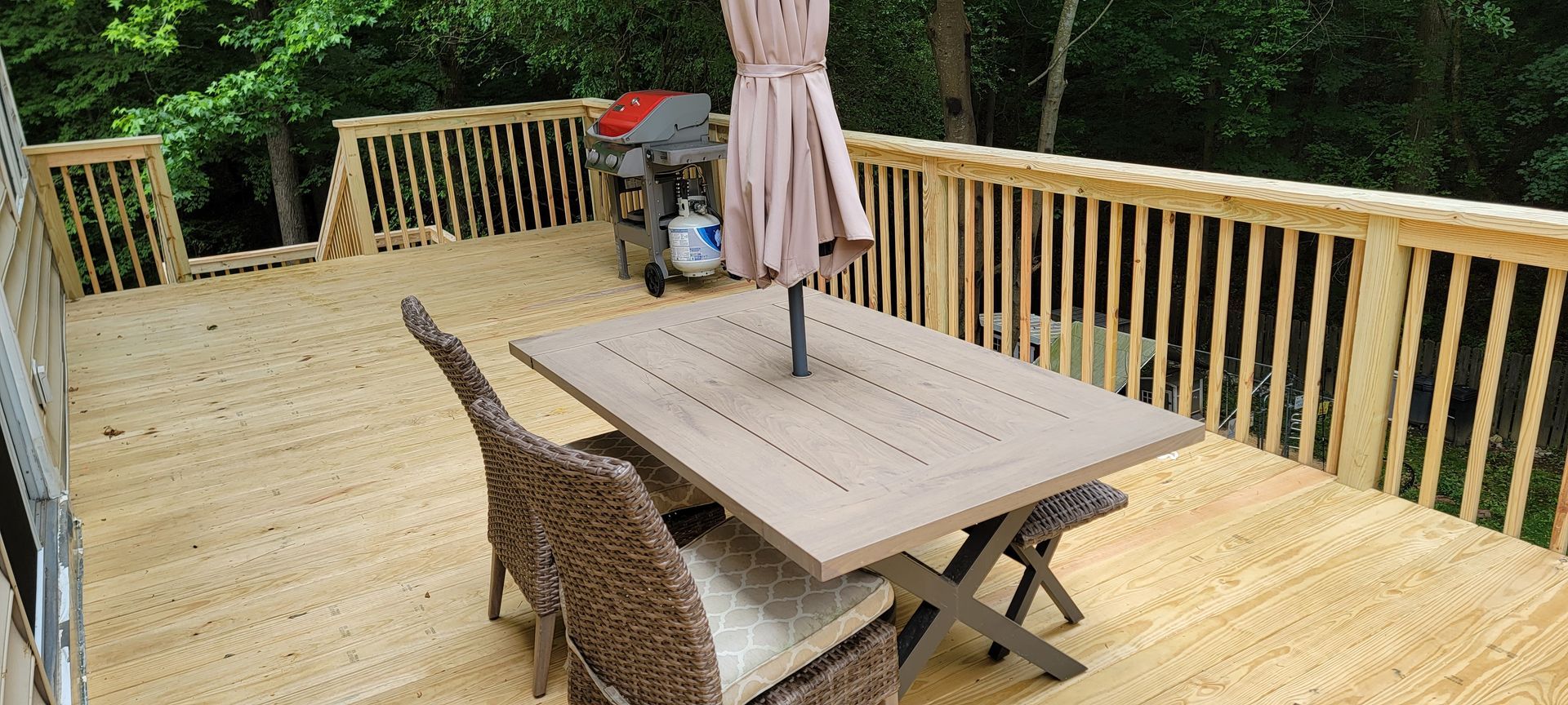 A wooden deck with a table and chairs and an umbrella.