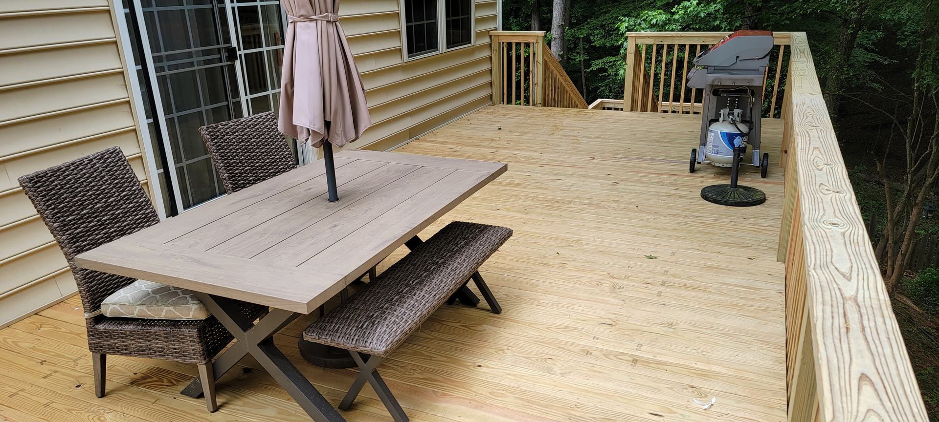A wooden deck with a table and chairs and an umbrella.