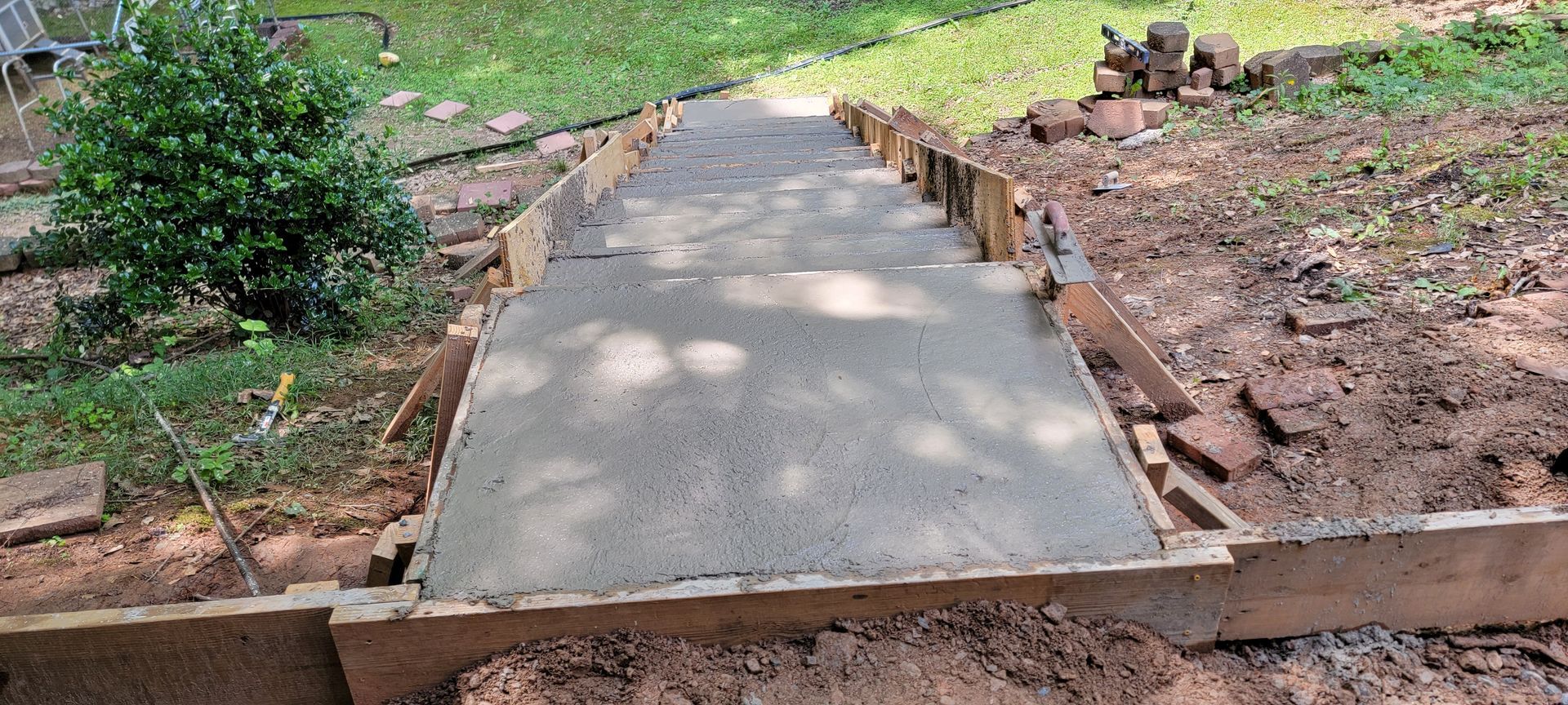 A concrete walkway is being built in a backyard.