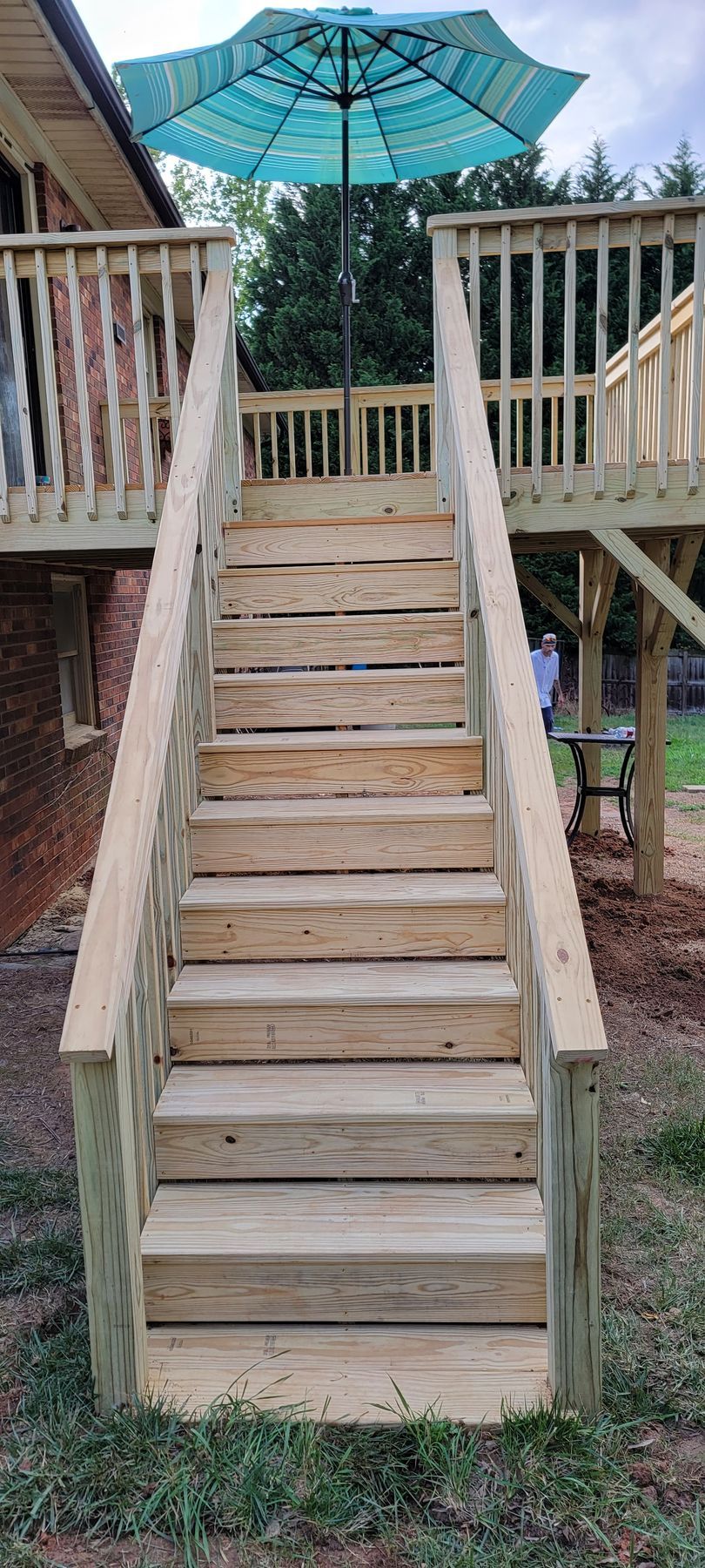 A wooden deck with stairs and an umbrella on top of it.