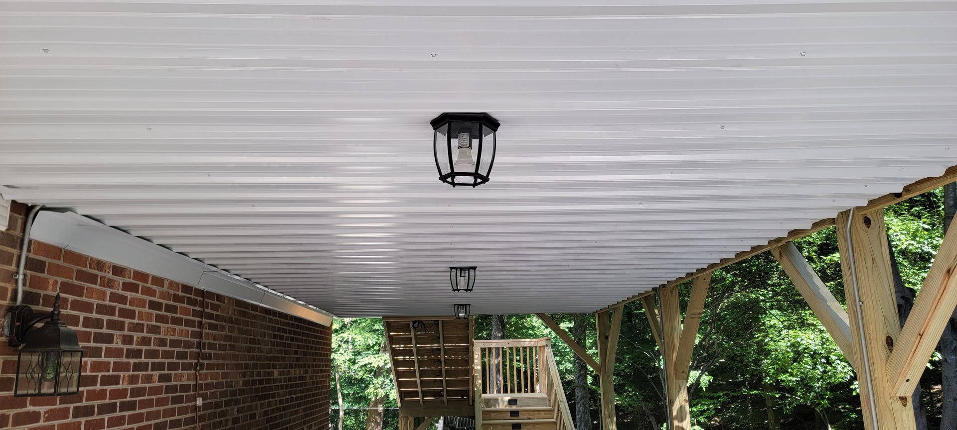 The ceiling of a carport with a brick wall and a white roof.