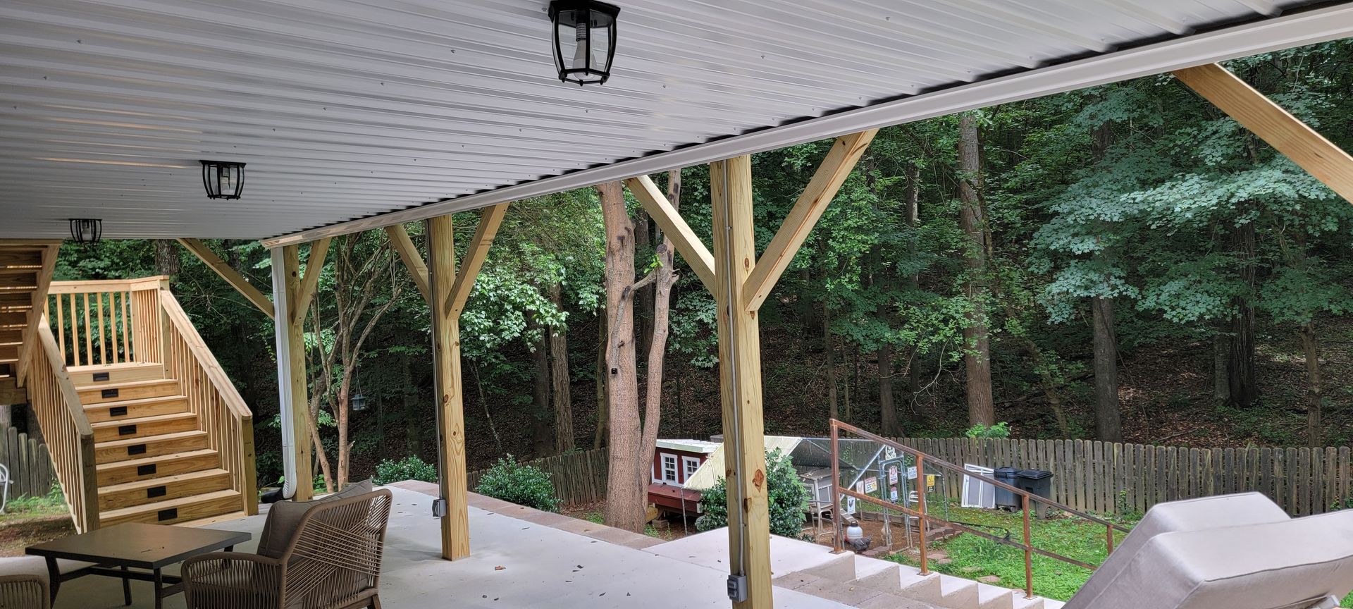 A covered porch with a table and chairs and a wooden deck.
