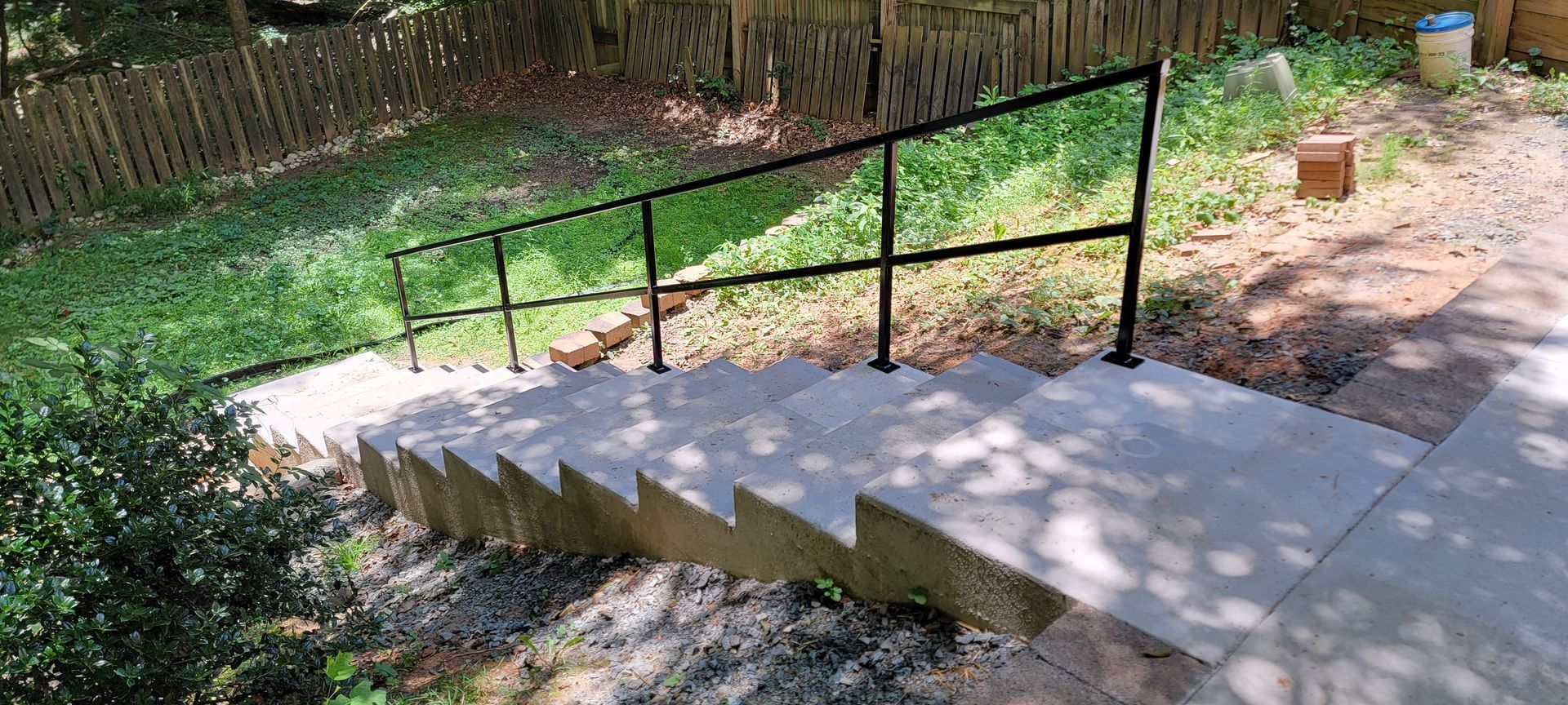A set of concrete stairs with a metal railing going up a hill.