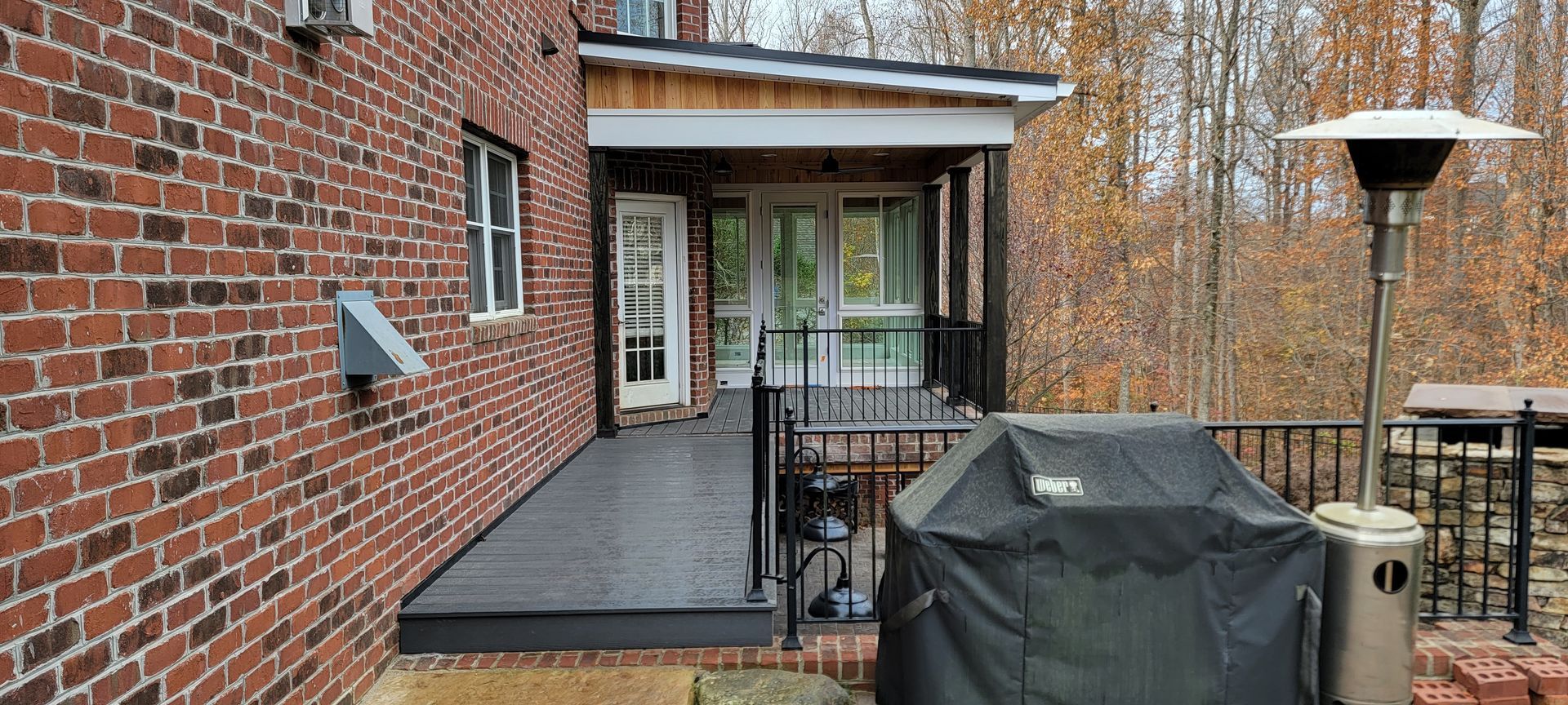 A brick house with a porch and a grill on it.