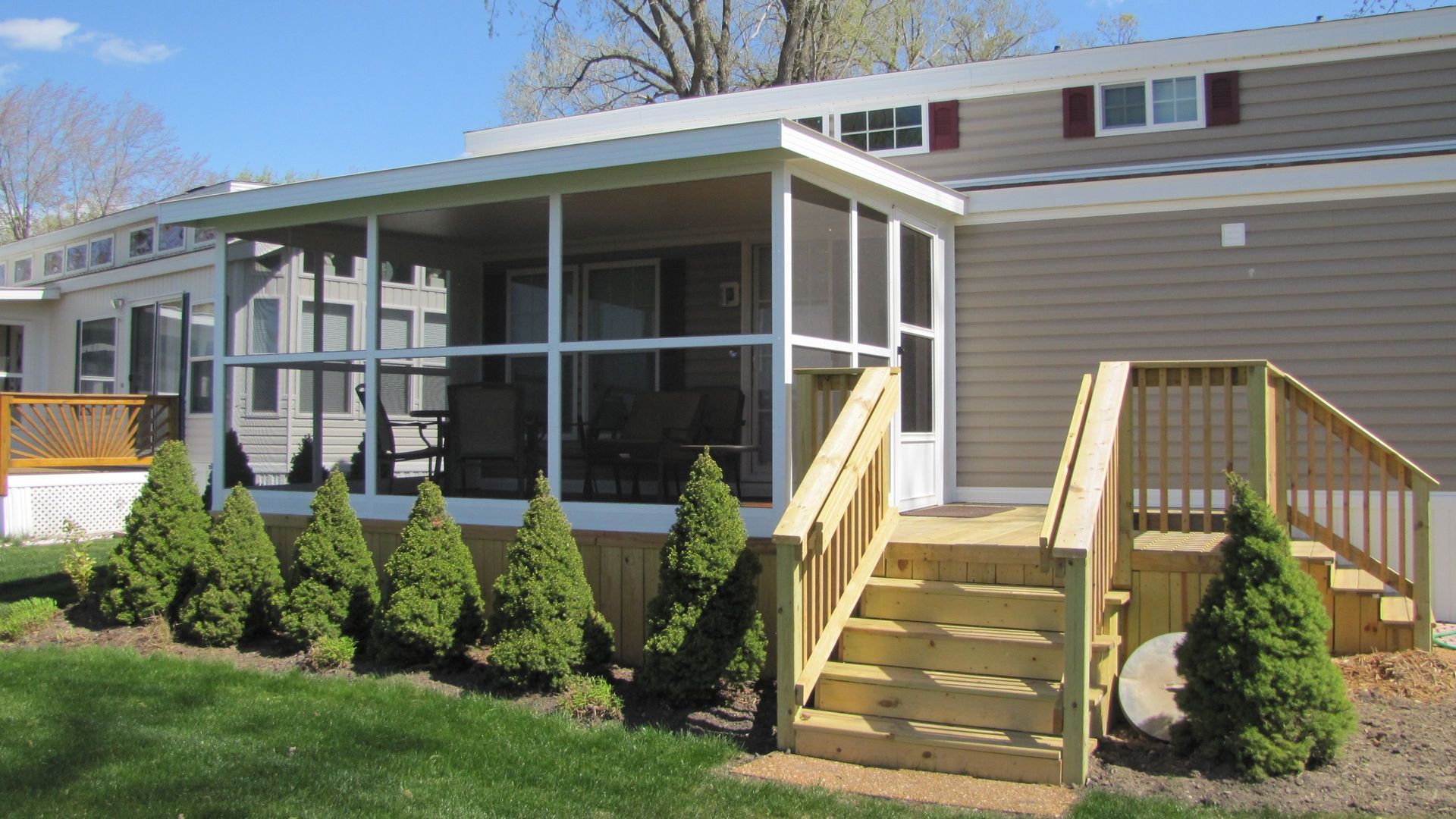 A mobile home with a screened in porch and stairs