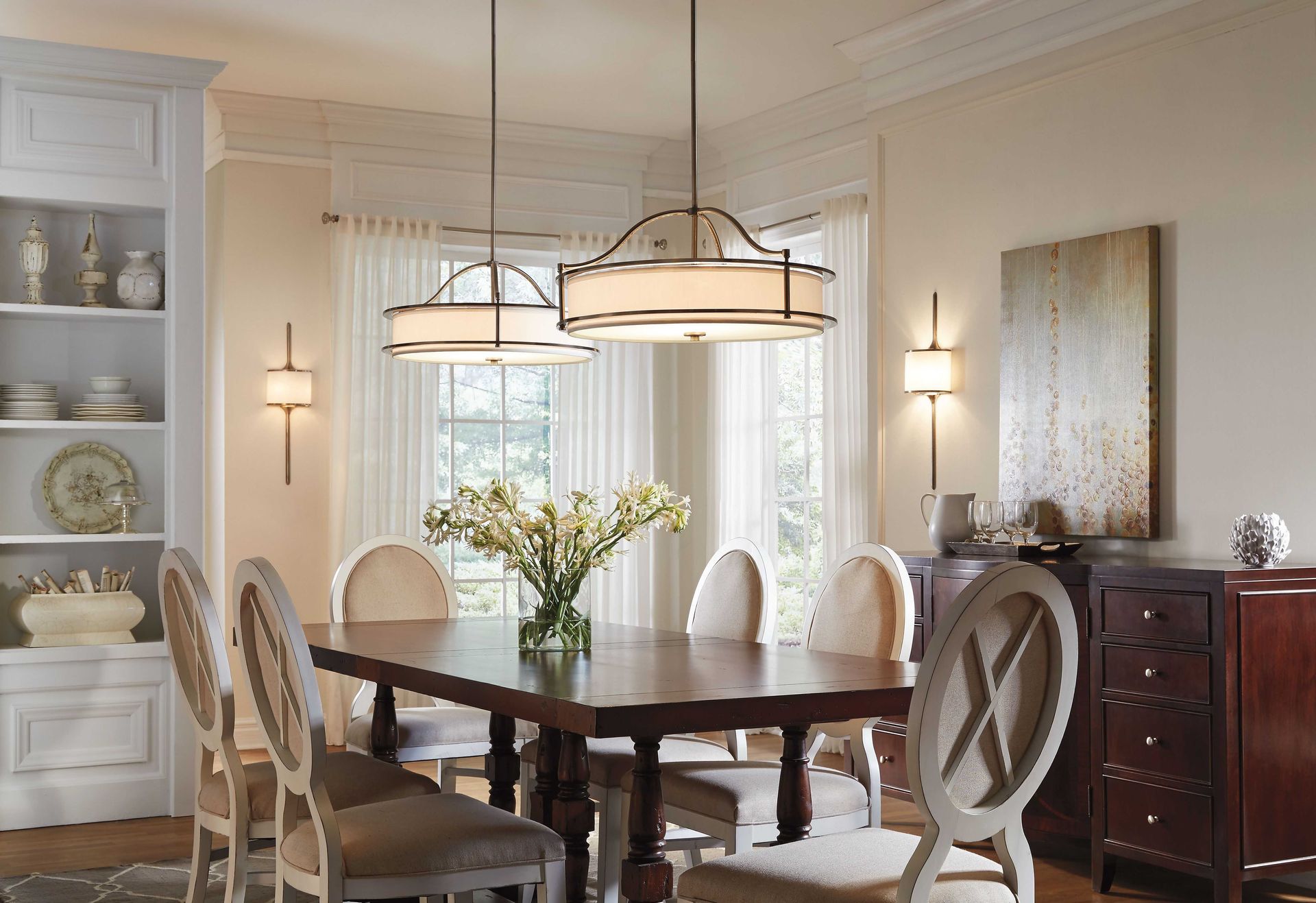 Elegant dining room with a dark wood table, six upholstered chairs, two pendant lights, a built-in bookshelf, and artwork.