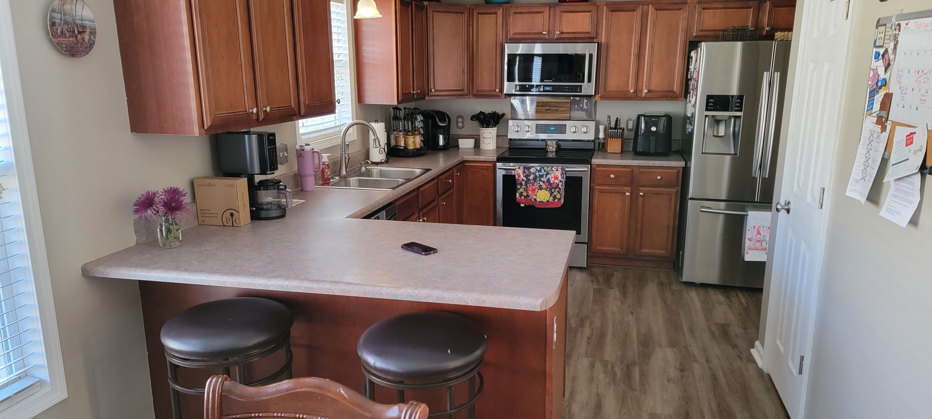 A kitchen with wooden cabinets , stainless steel appliances , a refrigerator and a sink.