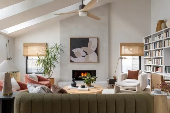 A living room with a couch , chairs , a fireplace and a ceiling fan.