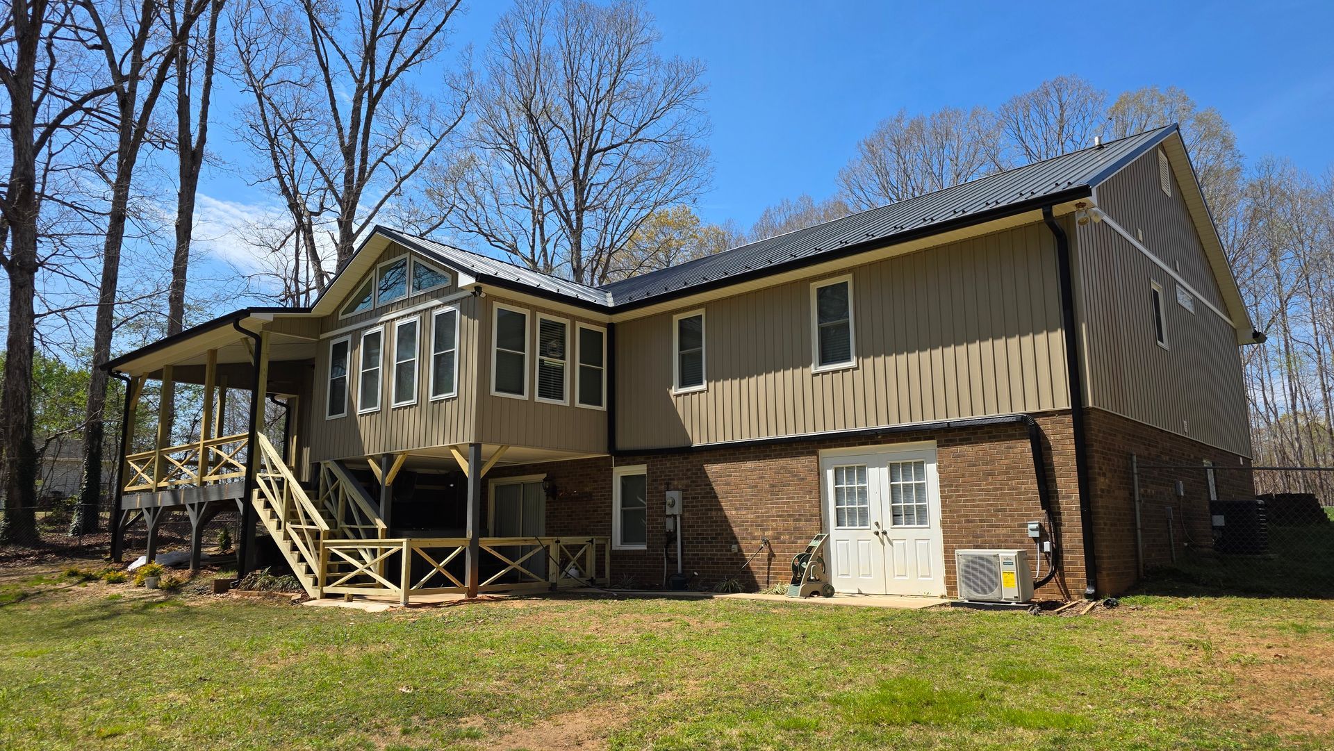 A large house with a porch and stairs is sitting on top of a lush green field.