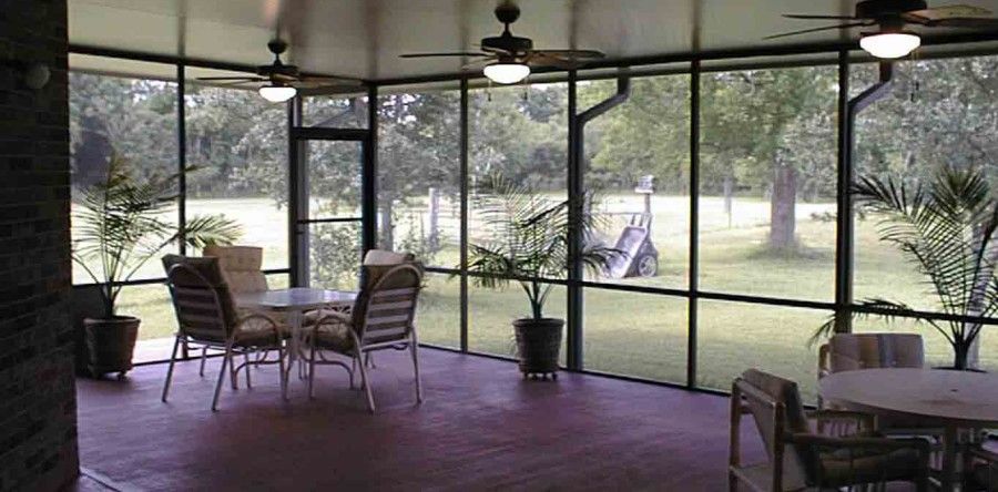 A screened in porch with a table and chairs