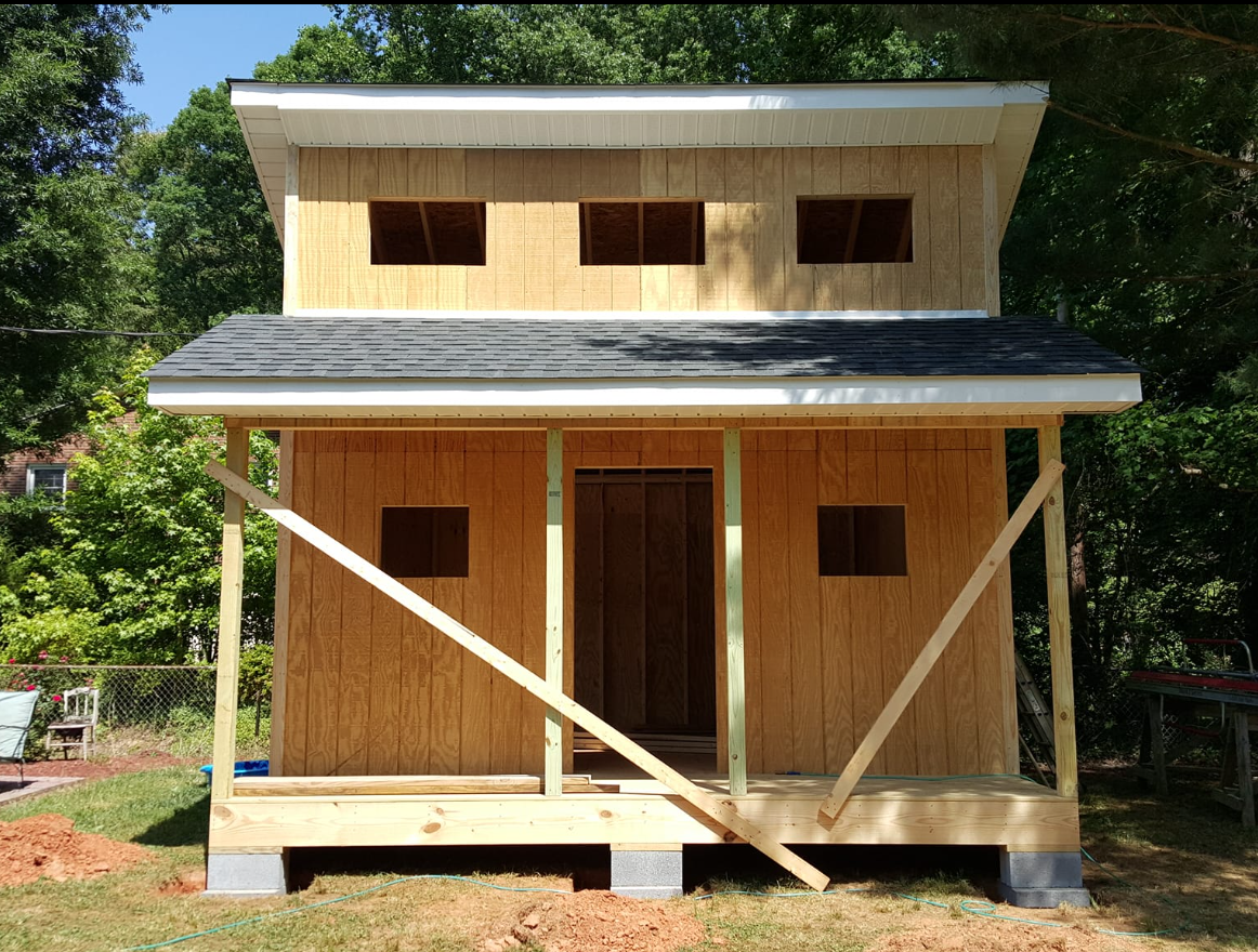A small wooden house is being built in a backyard