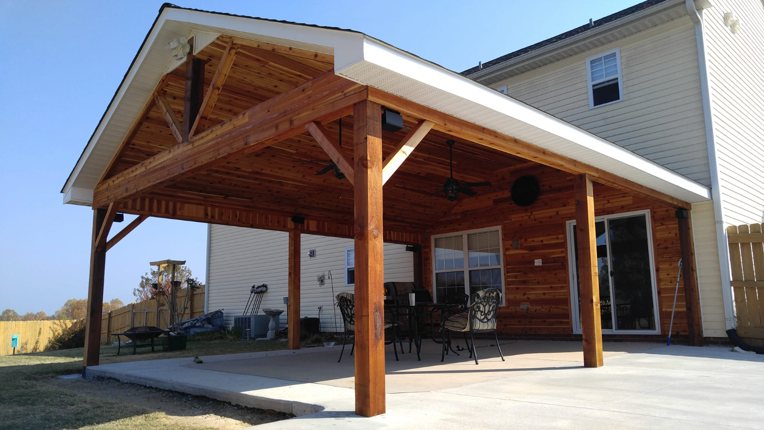 A large wooden covered patio area in front of a house