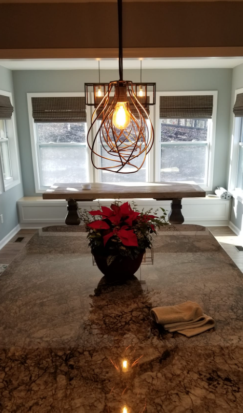 A dining room with a table and a vase of flowers on the counter.
