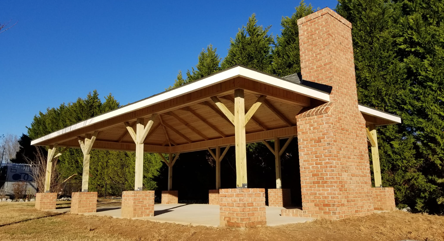 A wooden pavilion with a brick chimney on top of it.