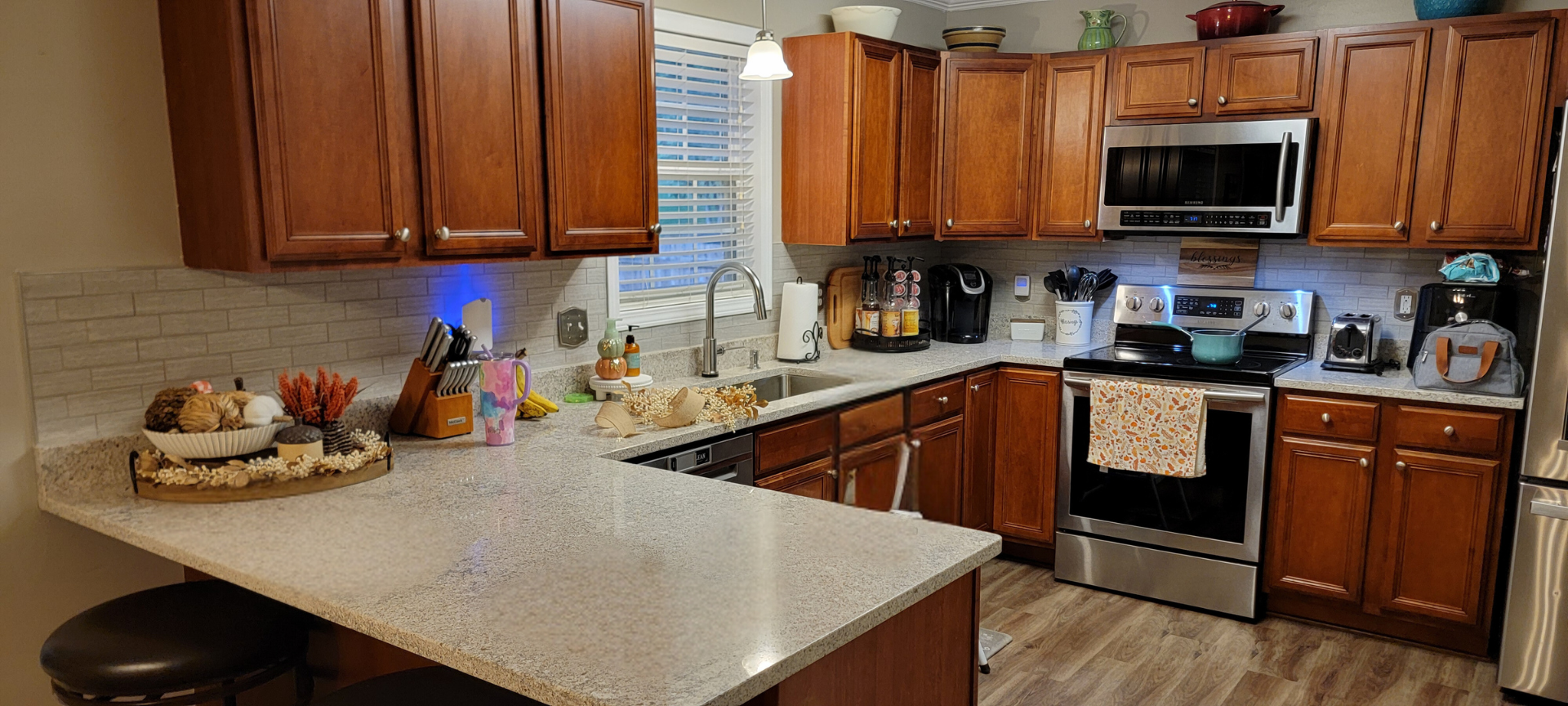 A kitchen with wooden cabinets , granite counter tops , stainless steel appliances and a stove.