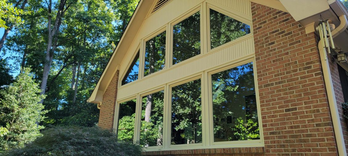 A large brick house with a lot of windows and trees in the background.