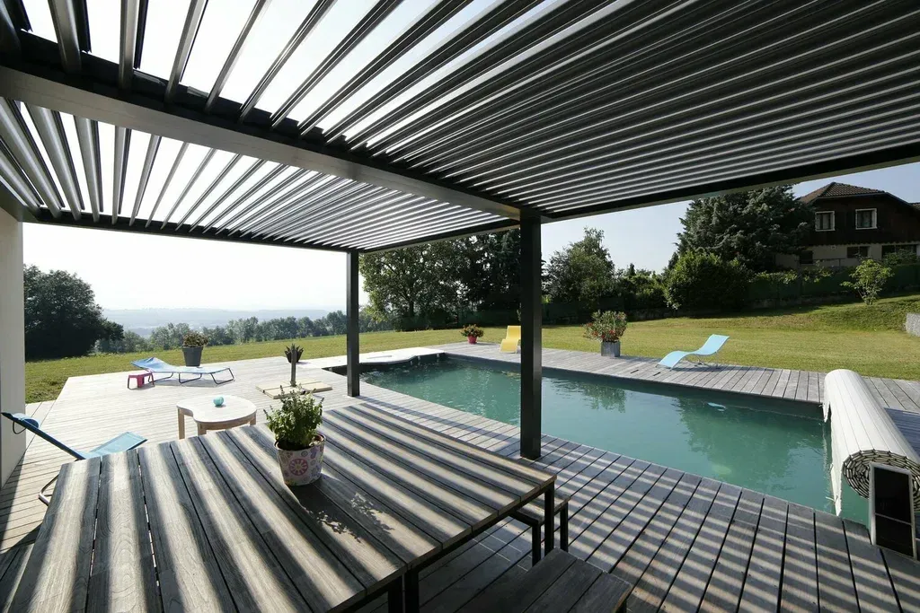 A table and chairs under a pergola overlooking a swimming pool