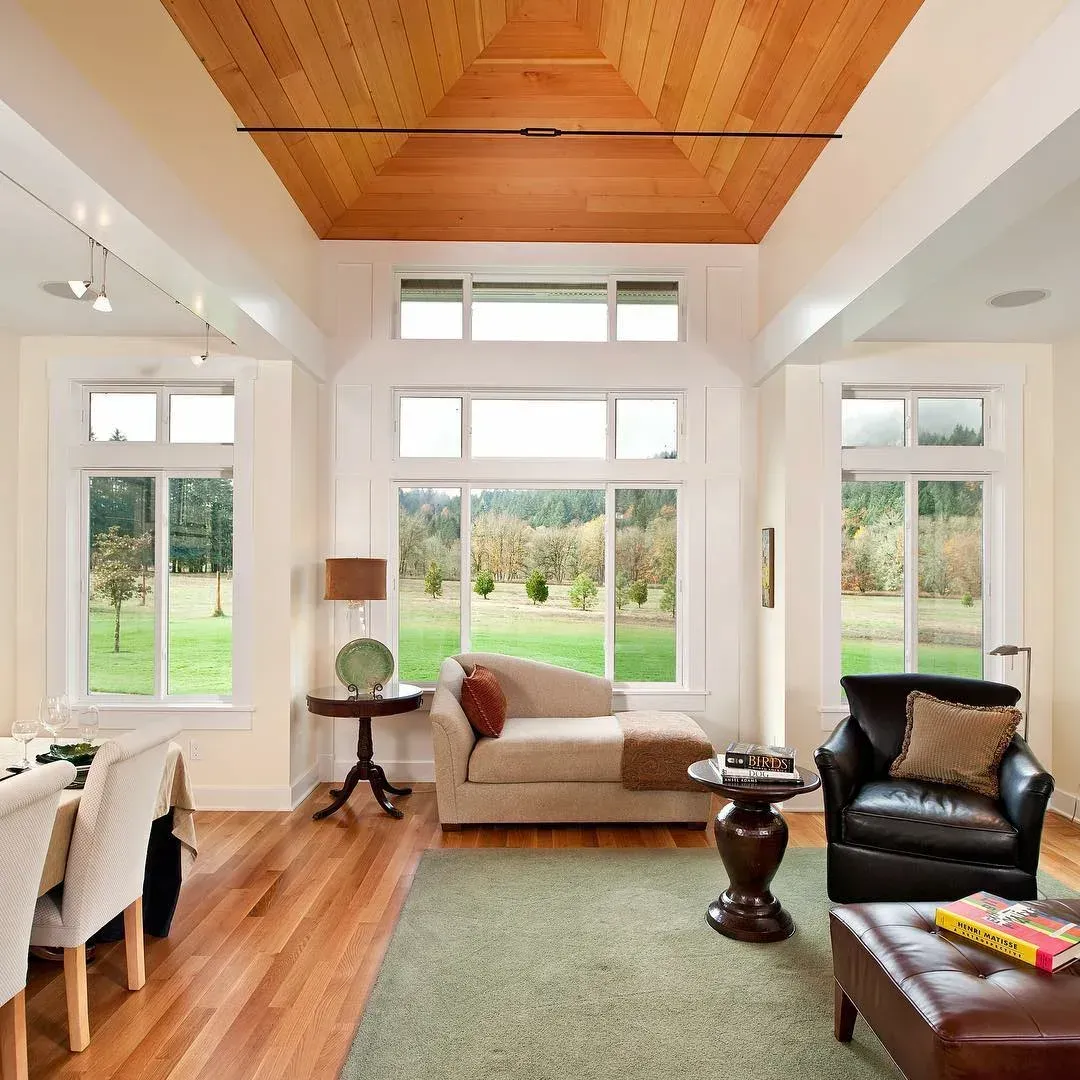 A living room with a wooden ceiling and lots of windows