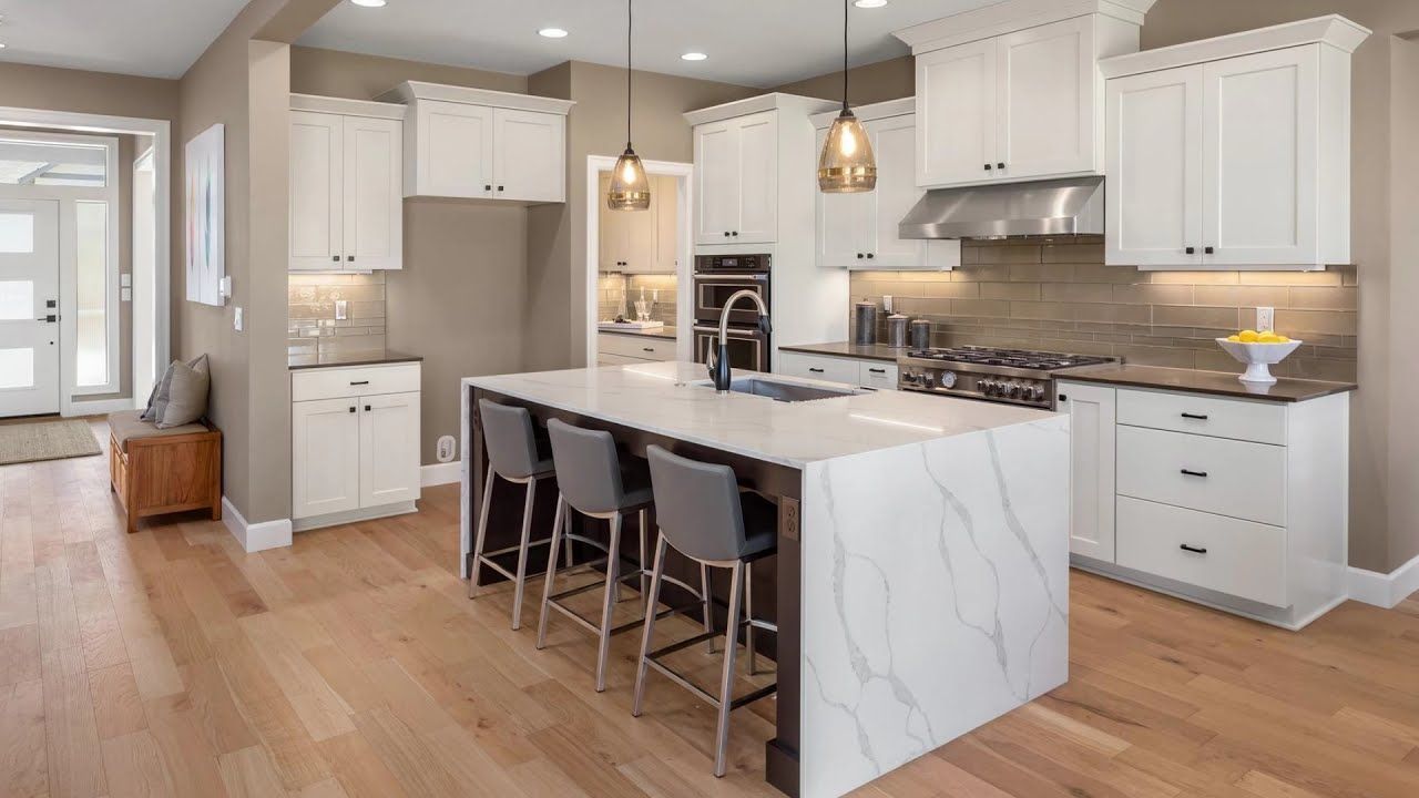 A kitchen with white cabinets and a large island in the middle.