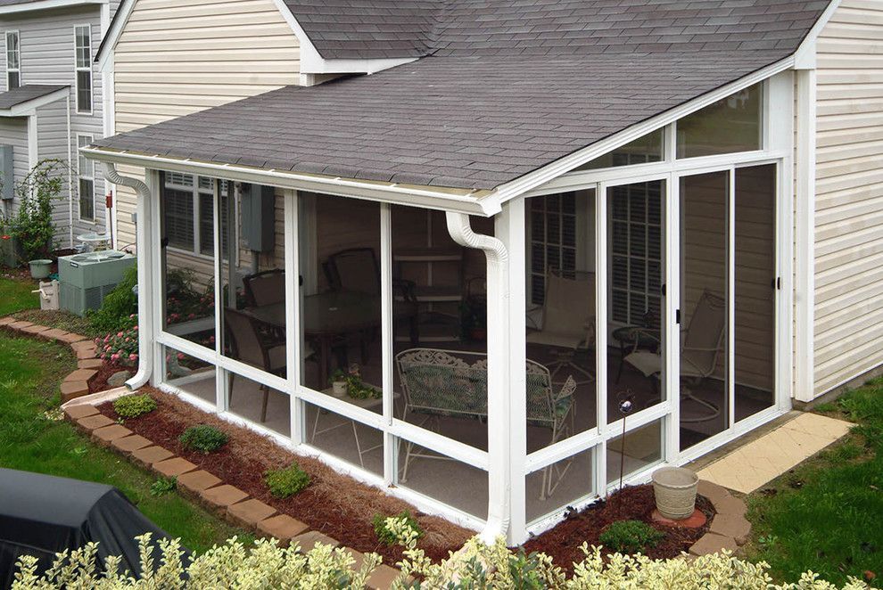 A screened in porch is attached to the side of a house.