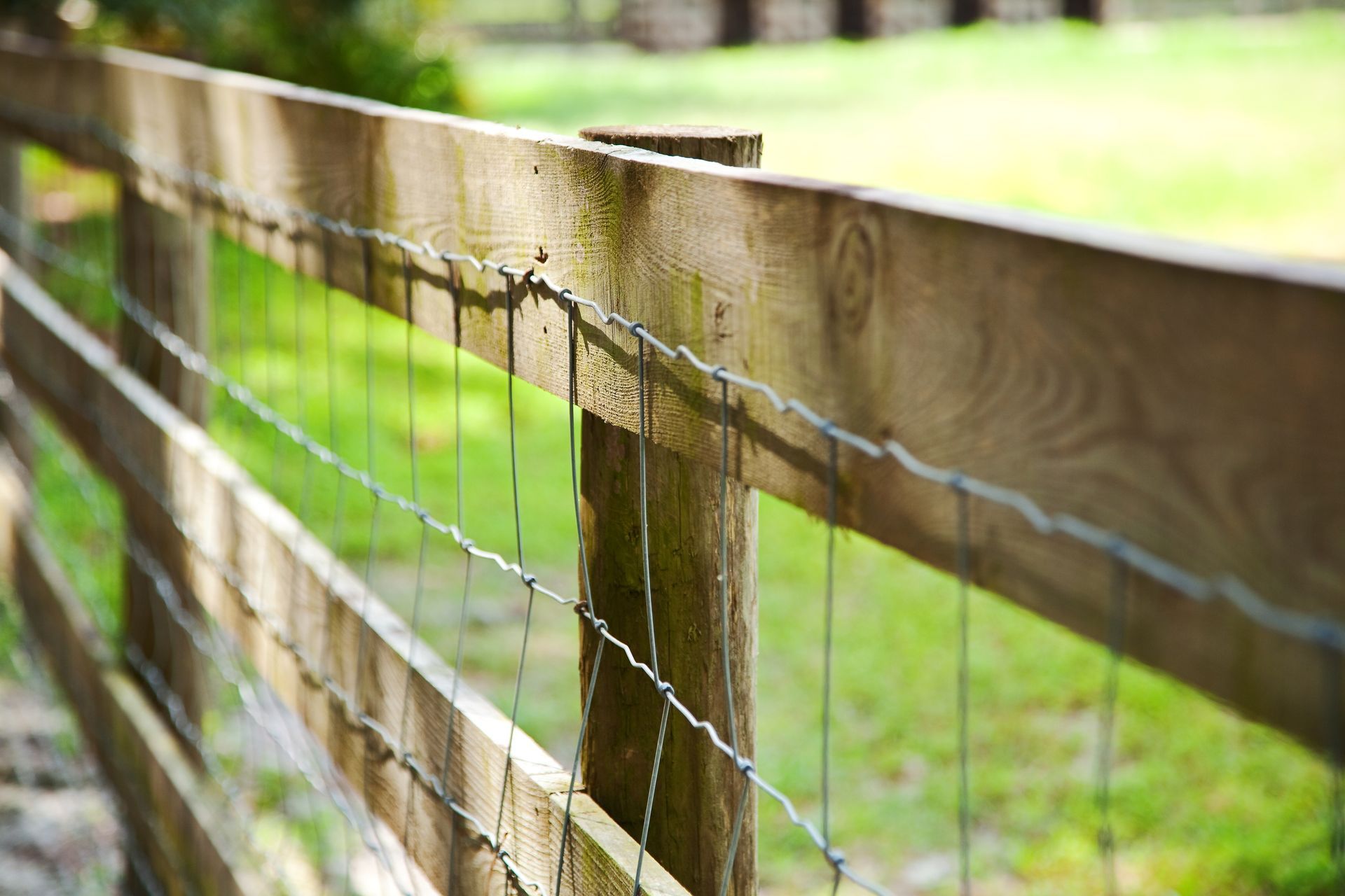 Diagonal woven wire fence on wooden slabs.