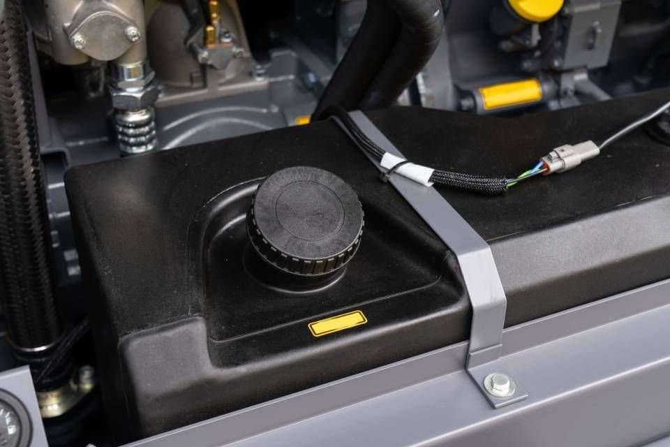 Black tank with a cap, part of machinery, held down by a silver strap.