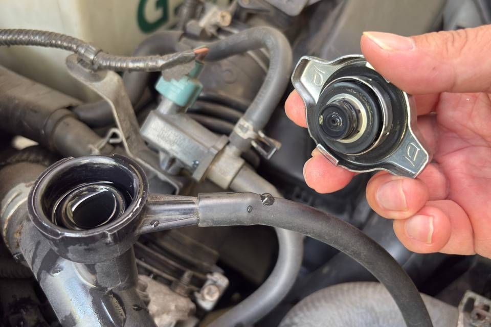 Person holding a car radiator cooling fan assembly in a garage.