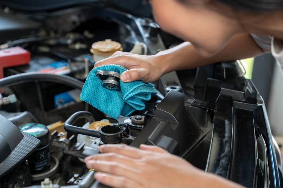 Person holding a car radiator cooling fan assembly in a garage.