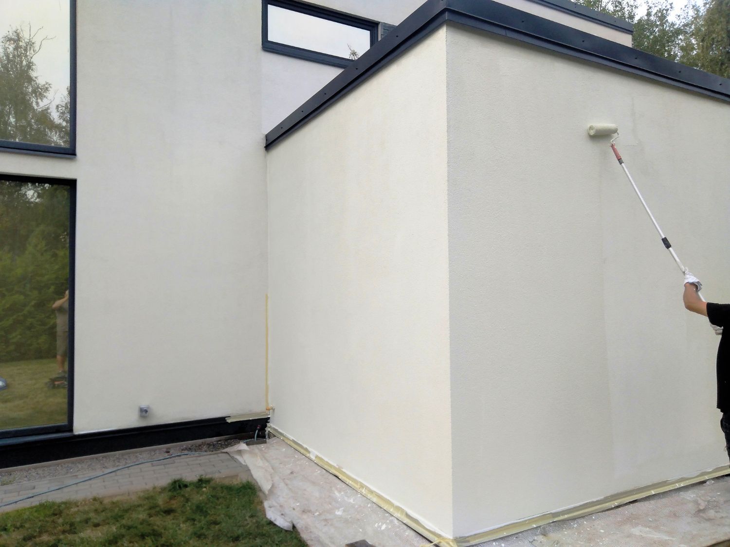 A man is painting a white wall with a roller.