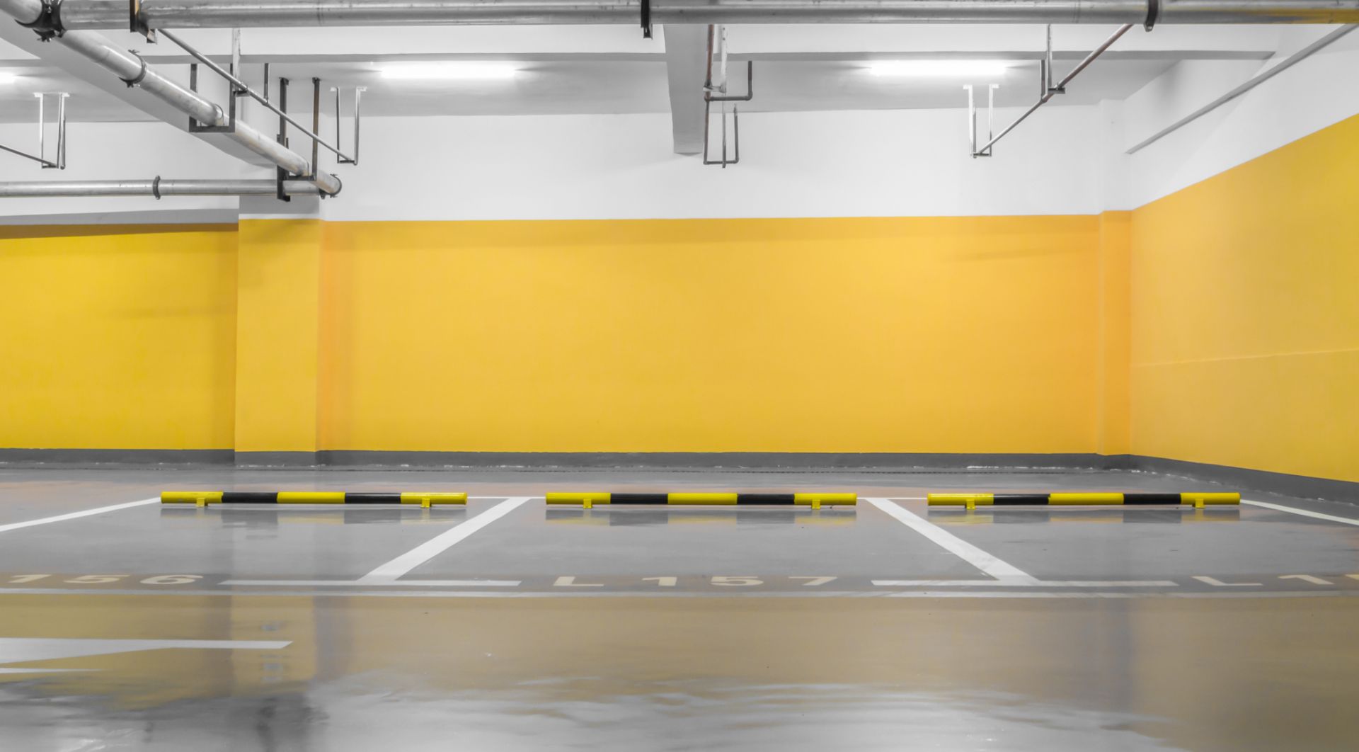 An empty parking garage with yellow walls and a concrete floor.