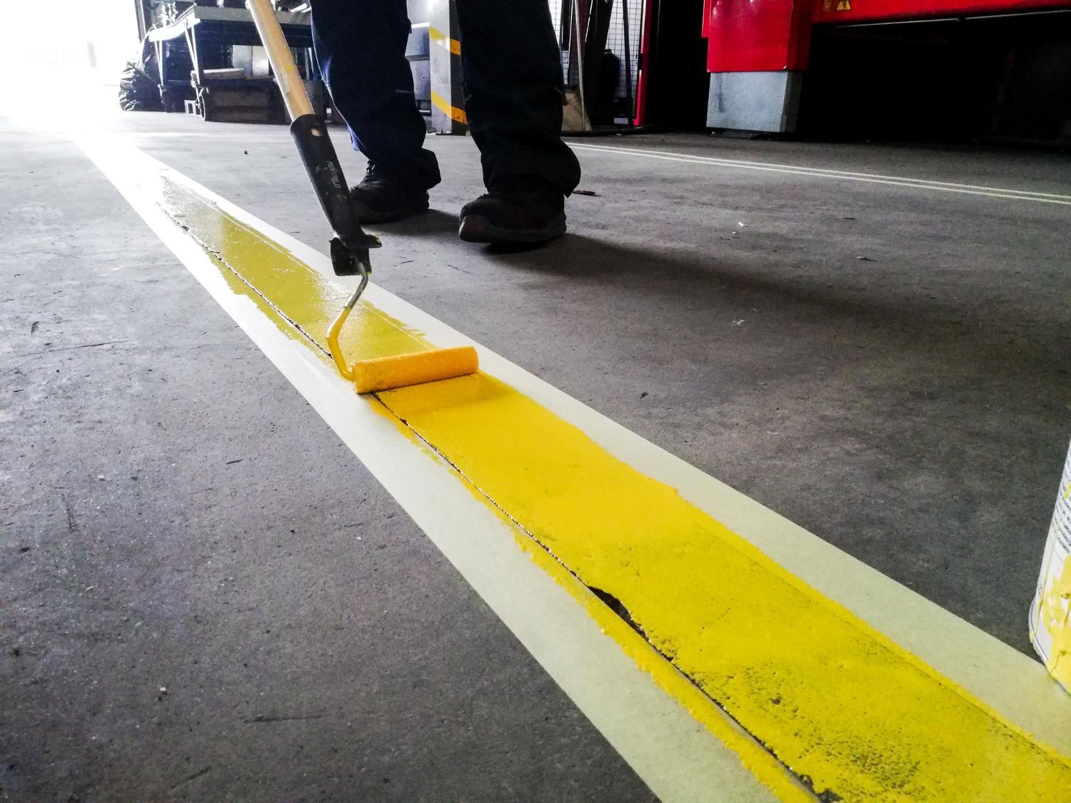 A person is painting a yellow line on the floor