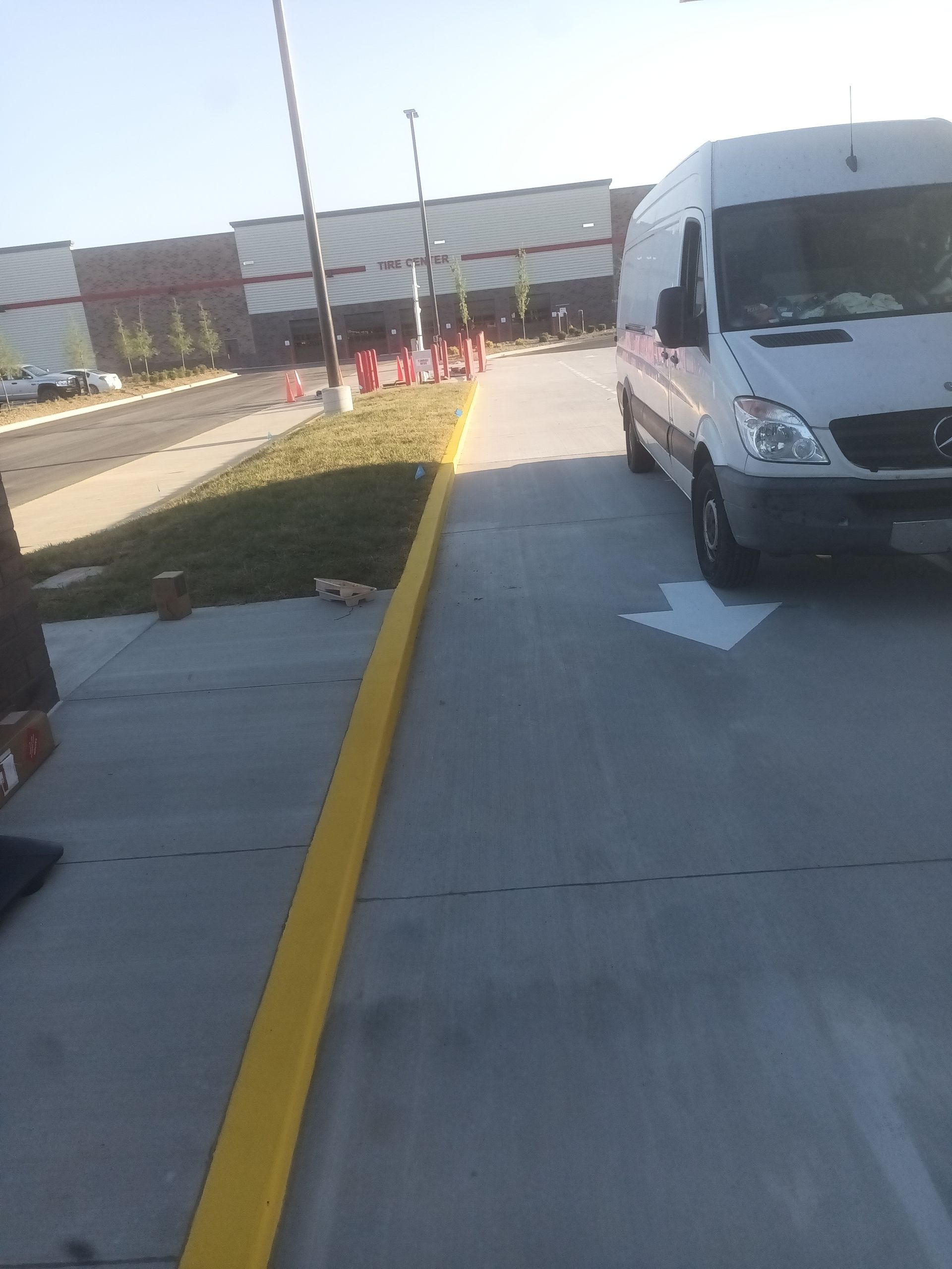 Fresh yellow curb paint on sealed concrete at commercial property driveway