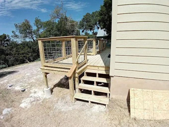 Wooden deck with steps next to a house with light tan siding.