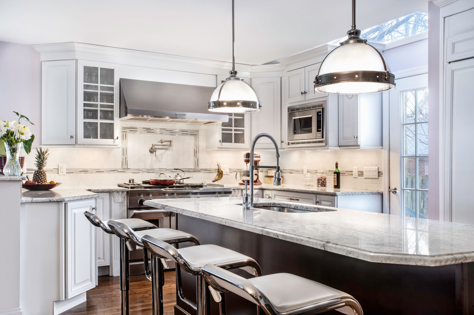 Modern kitchen with marble countertops and lighting fixtures.