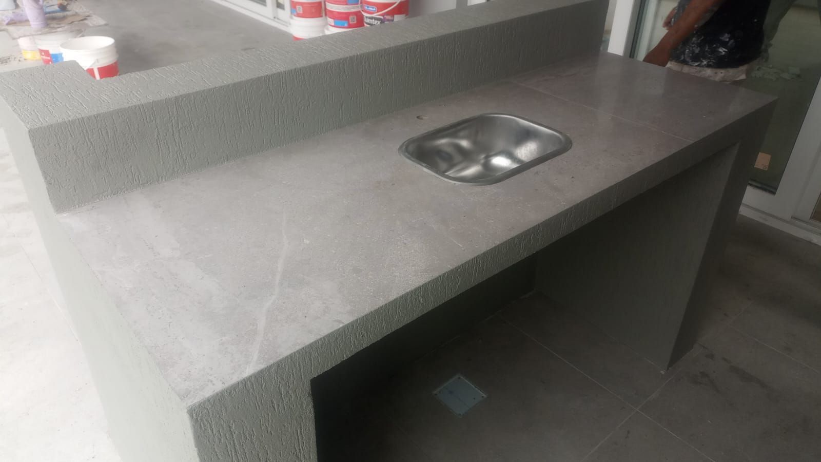 Encimera gris con fregadero empotrado de acero inoxidable en una cocina o área de trabajo.