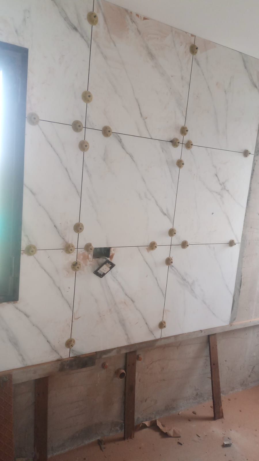 Pared alicatada con paneles que imitan el mármol, remaches decorativos y una pequeña abertura para toma de corriente.