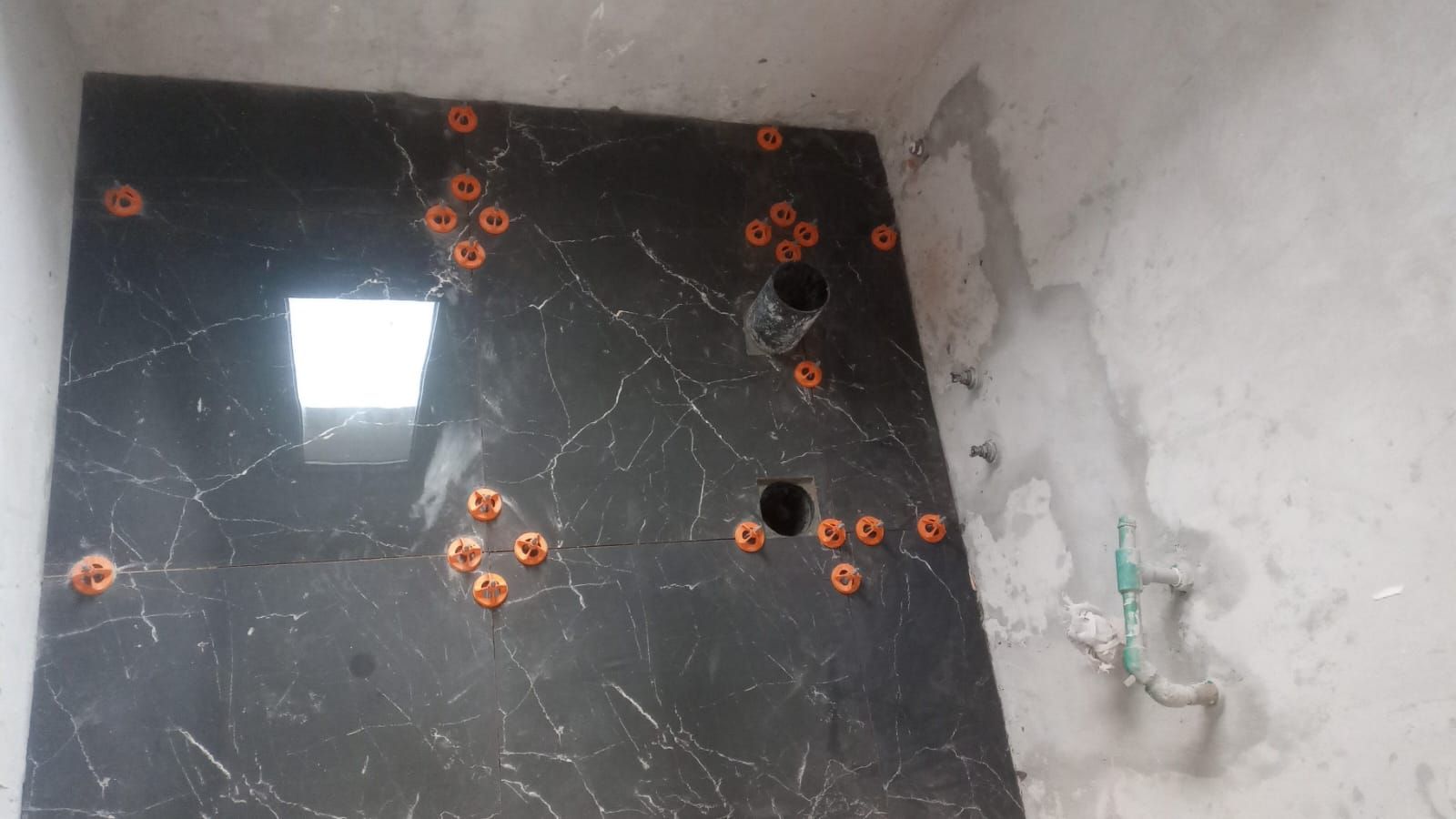 Suelo de baldosas negras con varias tomas de corriente de color naranja y una pared blanca con el cableado a la vista.