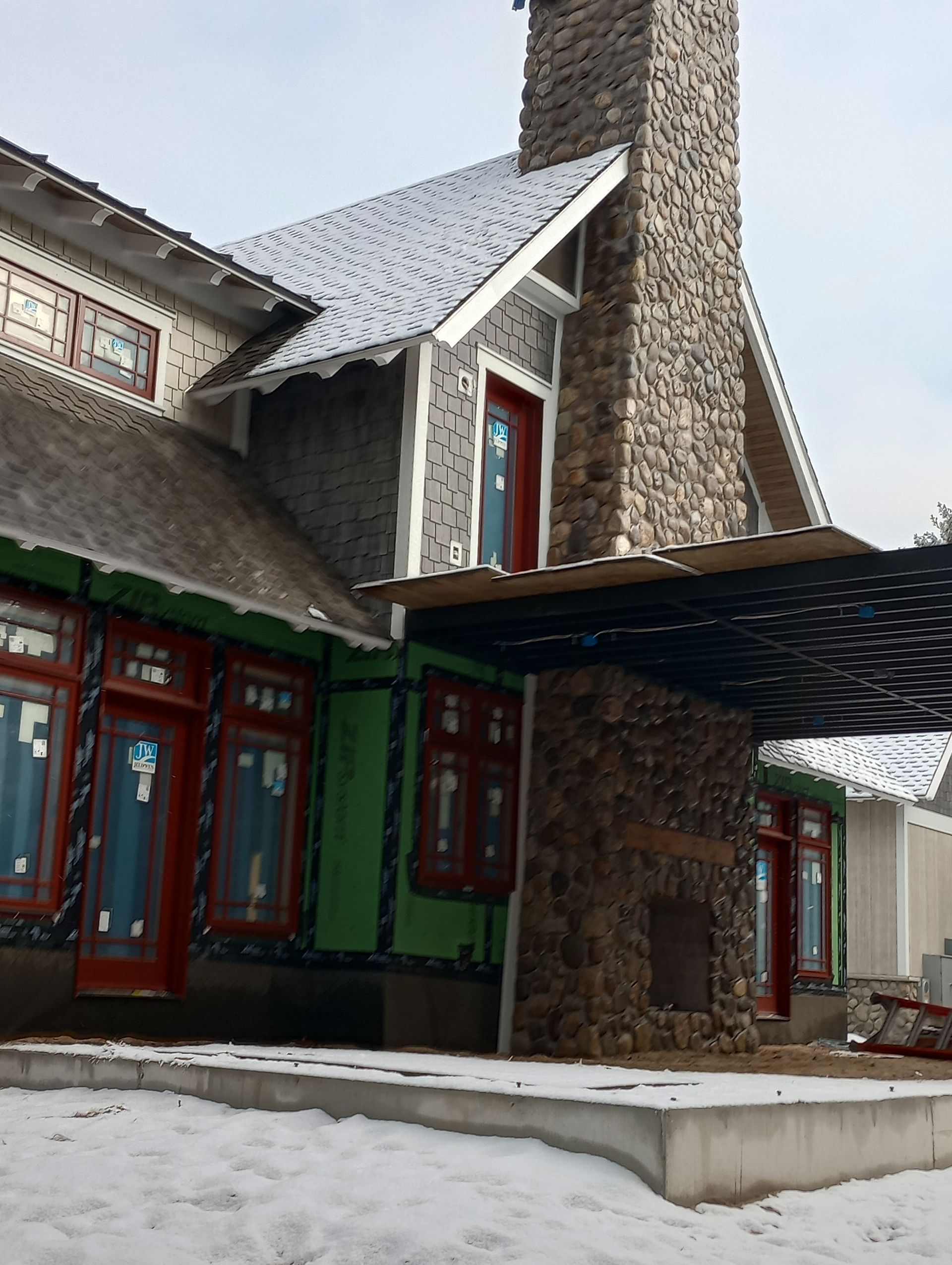A house with a stone chimney is being built in the snow