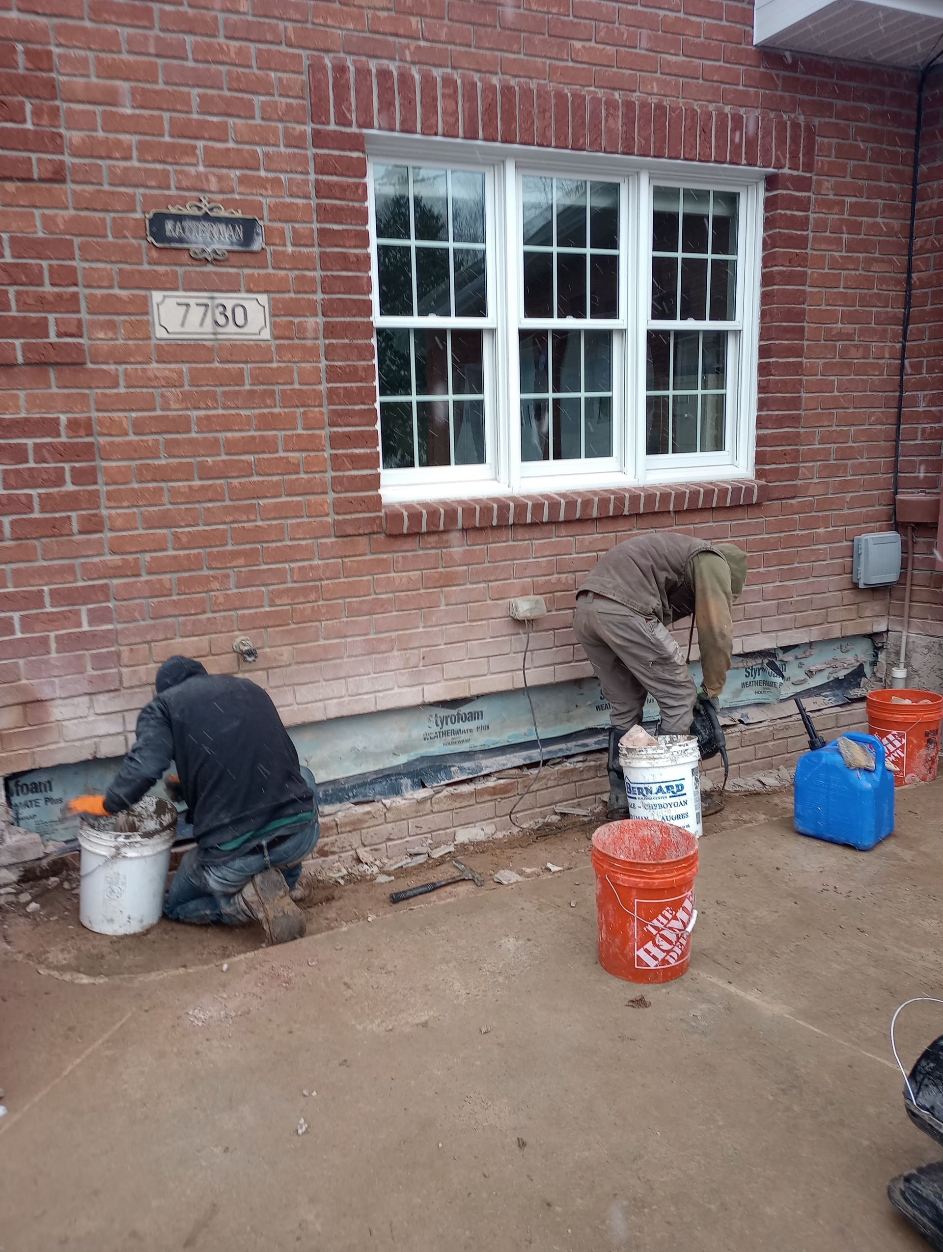 A group of men are working on the side of a brick building.