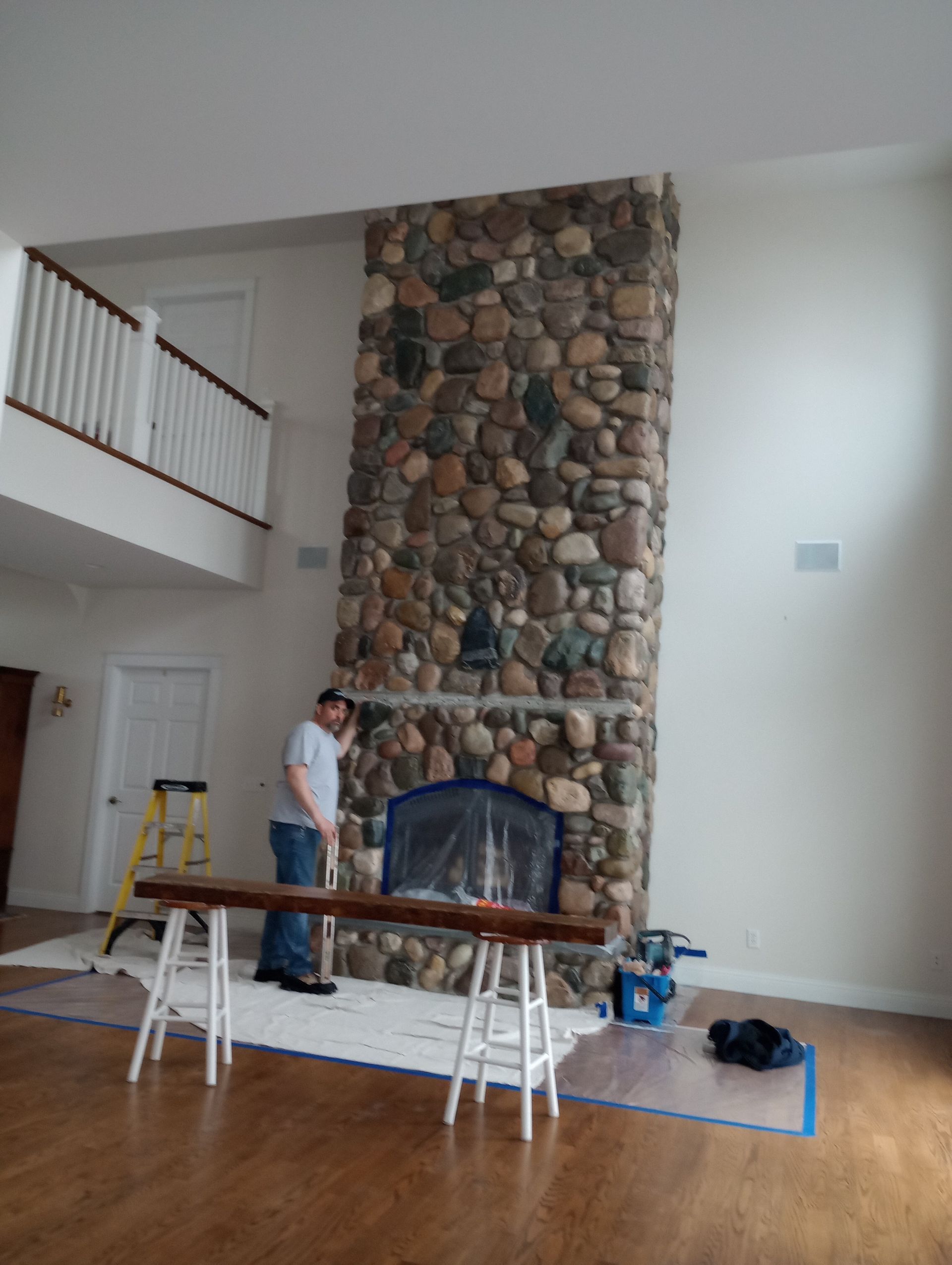 A man is standing in front of a large stone fireplace