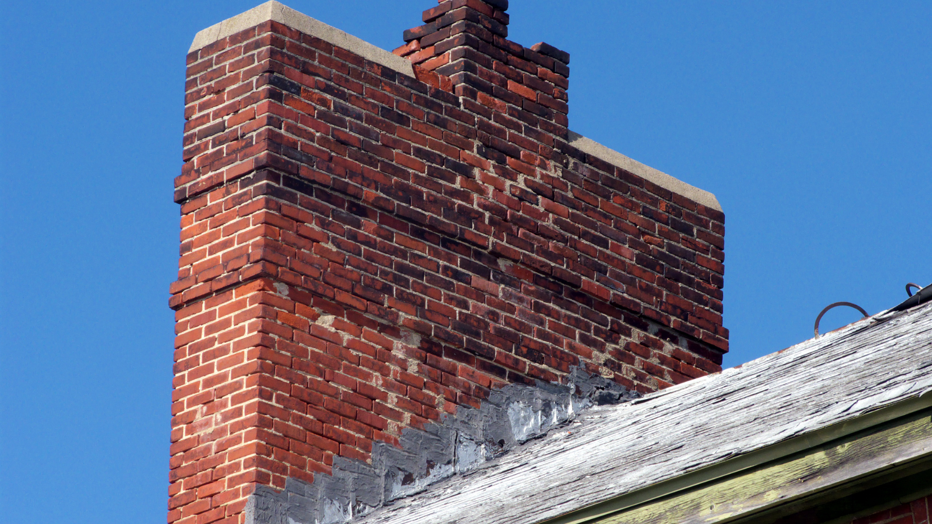 A brick chimney is sitting on top of a roof.