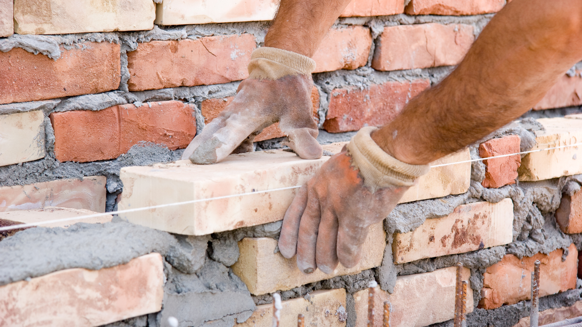 A man is laying bricks on a brick wall.