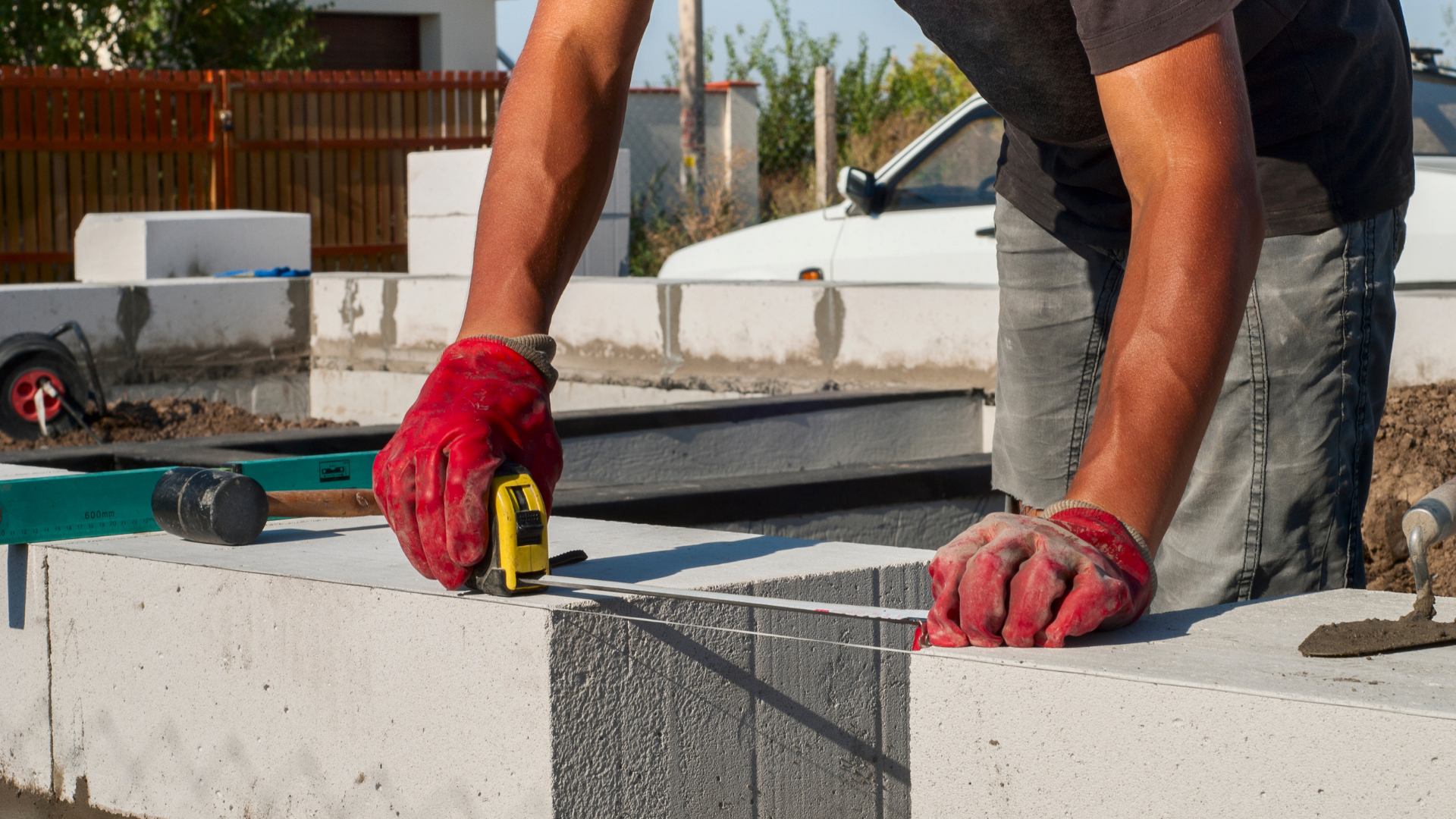 A man is measuring a piece of concrete with a tape measure.